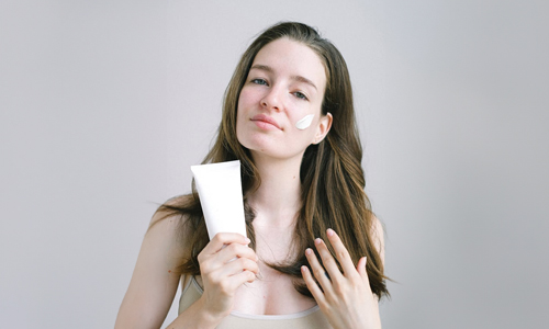 Woman with product on hand and face