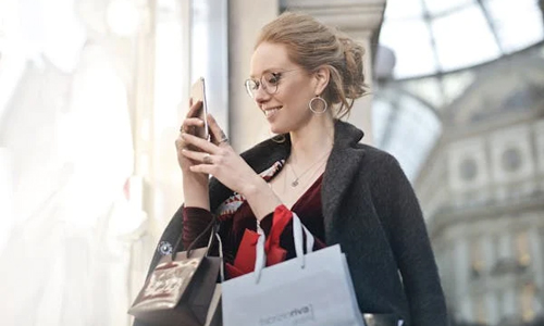 Woman with shopping bags and mobile in hand