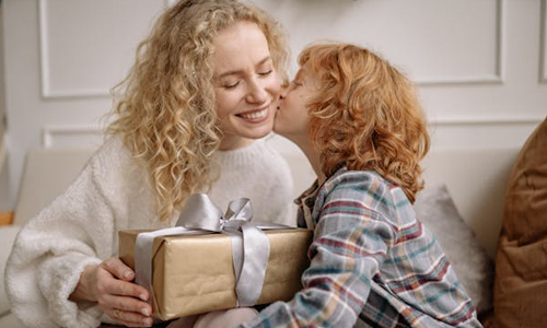 Child kissing mom with gift in hand