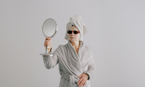 Woman with sheet mask and coolers with mirror in hand