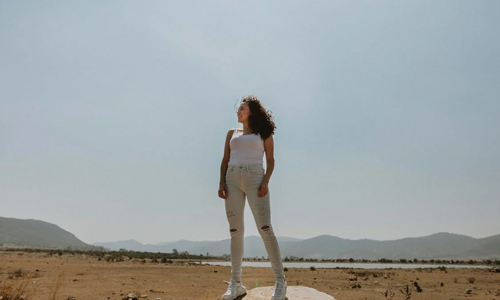 Woman in white tank top and ripped jeans