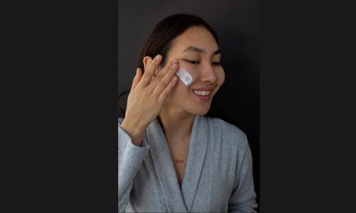 Woman applying moisturizer