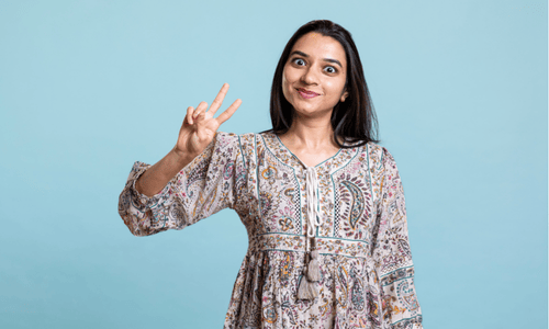 Happy Iwoman making a peace sign with her hand and smiling confidently.