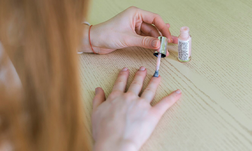 Woman applying nail polish in dark shade.