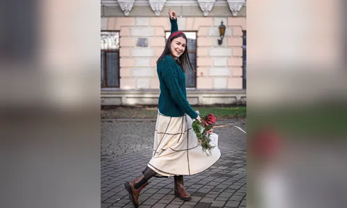 A young woman walking outside while wearing a stylish holiday outfit.