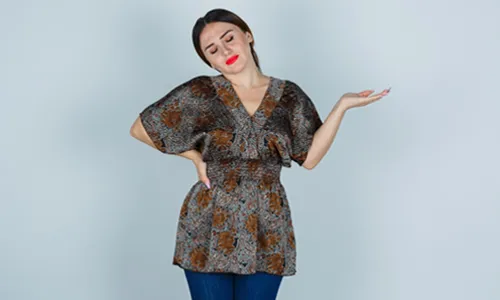 An expressive young woman posing in a studio while wearing a dynamic, flowing dress.