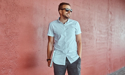 Man wearing a white shirt with an open collar and sunglasses outdoors
