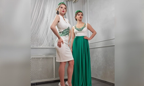 Two young women in short white dresses and high heels stand next to another woman in green pants. 